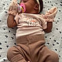 baby, sleeping, pacifier, mittens, headband, flower, pink, brown, clothing, blanket, pattern, infant, cute, cozy, newborn, socks, striped, laying_down, peaceful, soft