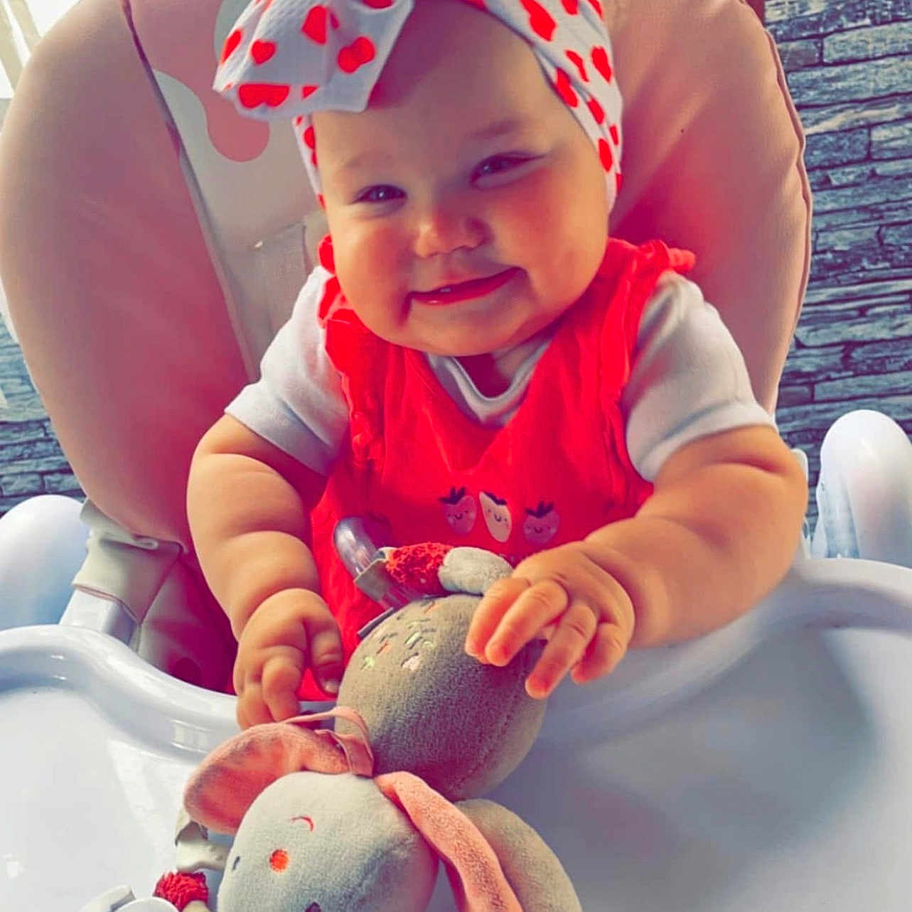 Keylia participe au concours pour gagner de l'argent avec cette photo : baby, child, clothing, cute, face, furniture, hands, happy, headband, high_chair, indoor, infant, pink, plush_bunny, polka_dot, red, smile, toy, white, window