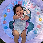 Zariah joined the competition — help win amazing prizes! baby, blanket, cartoon_design, closeup, curly_hair, cute, feet, flower_pattern, grass, happy, infant, onesie, outdoor, pink, play_mat, portrait, purple, relaxing, smiling, toes