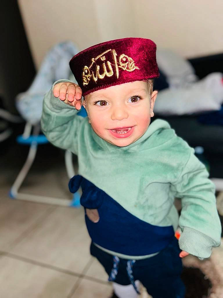 Aylan participe au concours pour gagner de l'argent avec cette photo : baby, baby_toddler_clothing, cap, child, costume, costume_hat, electric_blue, face, fashion_accessory, fictional_character, fun, happy, hat, headwear, joy, pattern, person, portrait_photography, room, sleeve