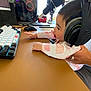 baby, pacifier, headphones, computer, keyboard, mouse, microphone, desk, hand, person, technology, indoor, monitor, wearing, clothing, cute, infant, electronics, reflection, window