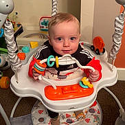 Lucas is registered to the contest to win money with this photo: activity, baby, background, child, clothing, colorful, cute, face, floor, footwear, hand, happy, indoor, infant, jumper, person, play, seat, smile, toys