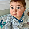baby, child, infant, onesie, striped_clothing, face, eyes, cheeks, mouth, skin, hair, hand, baby_bed, blanket, blue, white, indoor, portrait, cute, curious