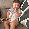 Damian joined the competition — help win amazing prizes! baby, child, infant, couch, pillow, toy, pacifier, bib, clothing, indoor, person, cute, chubby, sitting, looking, hand, feet, face, expression, home