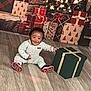 Kimani Mason joined the competition — help win amazing prizes! baby, child, smiling, indoor, christmas, holiday, gift, present, floor, wooden_floor, wrapped_gift, ribbon, onesie, happy, festive, decorations, lights, celebration, background, sitting
