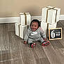 Kimani Mason is registered to the contest to win money with this photo: baby, child, smiling, sitting, nike, gray_clothing, shoes, gift_boxes, ribbons, chalkboard, flooring, wood_floor, indoor, portrait, happy, six_months, announcement, home, cute, young_child