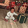 baby, child, gift_box, christmas_tree, presents, flooring, holiday, smiling, indoor, festive, decorations, red, green, gold, wrapped_gifts, happy, clothing, sitting, celebration, home