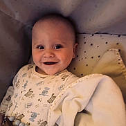 Jamie is registered to the contest to win money with this photo: baby, smiling, blanket, onesie, infant, cute, face, child, joyful, soft, comfort, lying, patterned_clothing, indoors, happy, young_child, sleeping_area, toy, beads, star_shaped_toy