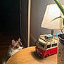 Tibou a rejoint le concours — aidez-le/la à gagner de superbes lots ! animal, blue_eyes, cat, cozy, curious, decor, dim_light, fluffy, furniture, home, indoor, lamp, light, pet, plant_leaf, potted_plant, shadow, table, toy_van, wooden_table