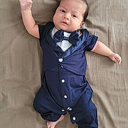 Kamel Eddine participe au concours pour gagner de l'argent avec cette photo : baby, infant, tuxedo, onesie, bow_tie, clothing, laying, bed_sheet, hand_raised, foot, cute, portrait, child, person, indoors, fabric, skin, face, hair, button