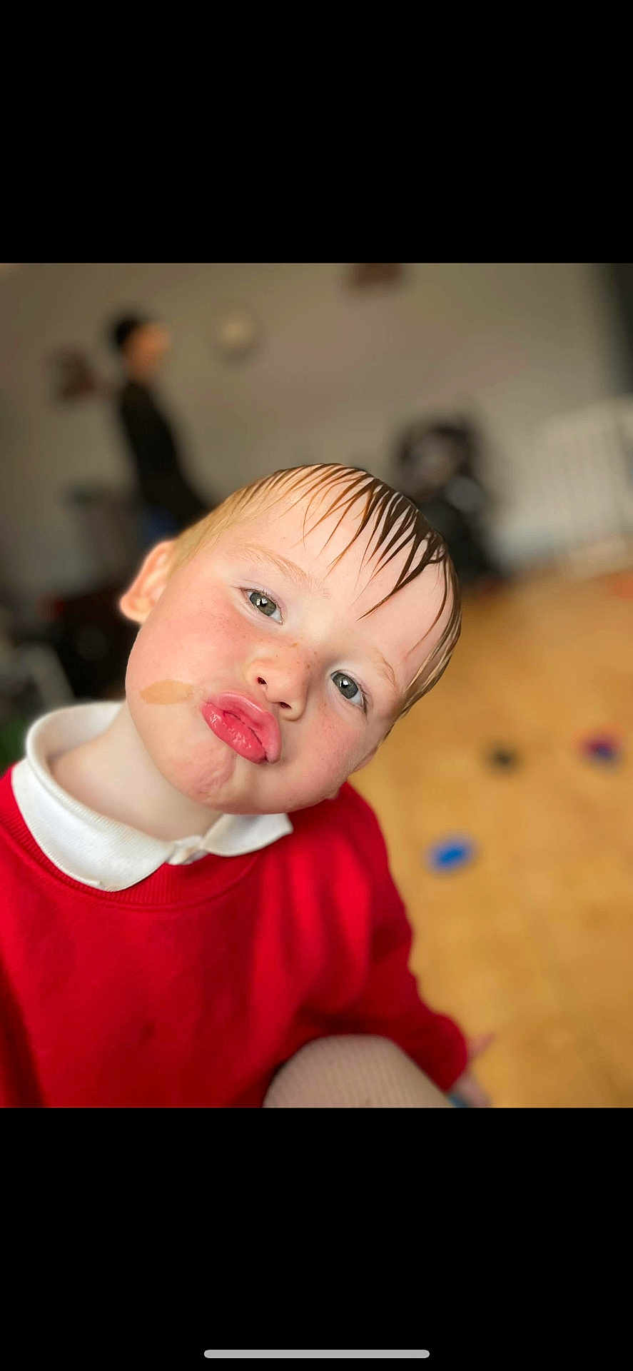 Archie is registered to the contest to win money with this photo: child, face, pout, wet_hair, red_sweater, white_collar, indoor, floor, toy, person, playful, cute, portrait, blurry_background, expression, skin, head, hair, young, funny_face
