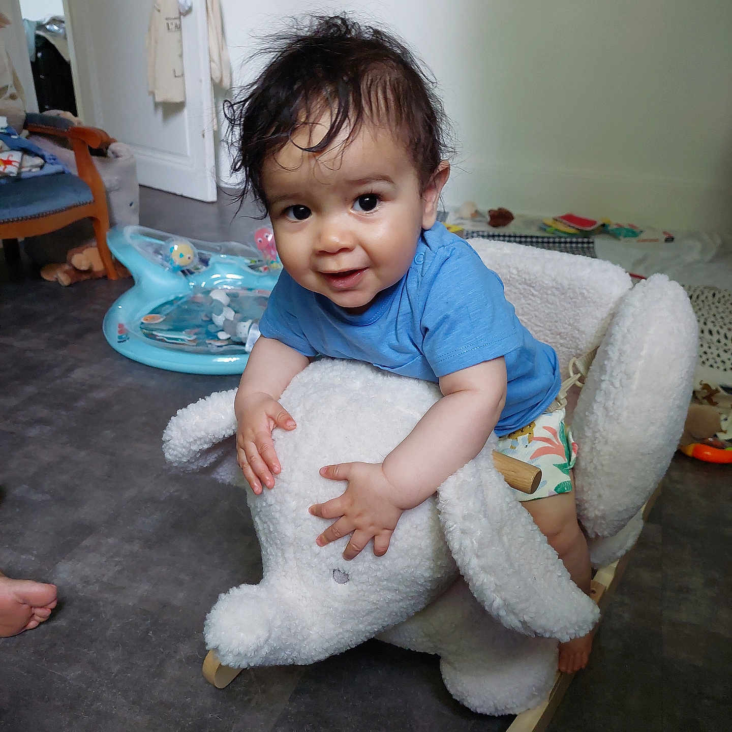 Maël a rejoint le concours — aidez-le/la à gagner de superbes lots ! blue_shirt, child, elephant, face, floor, foot, furniture, hair, hand, happy, home, indoor, person, play_area, plush, rocking_toy, shorts, smiling, toddler, toy