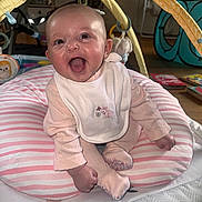 Sienna is registered to the contest to win money with this photo: baby, infant, smiling, happy, pink, bib, striped_cushion, toy, playmat, indoor, child, cute, clothing, face, person, sitting, home, floor, play_area, joyful