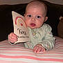 baby, infant, milestone_card, rainbow, pink_stripes, cushion, hand, face, eyes, mouth, clothing, onesie, indoor, portrait, child, person, cute, soft_lighting, expression, milestone