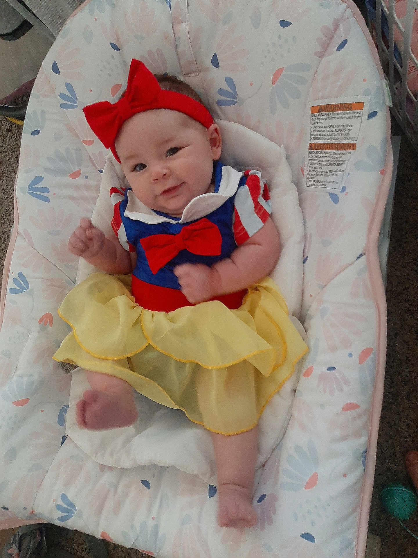 Muireann joined the competition — help win amazing prizes! baby, infant, child, smile, red_bow, yellow_skirt, blue_top, baby_seat, floral_pattern, indoor, cute, happy, portrait, headband, furniture, carpet, footwear_absent, skin, clothing, person