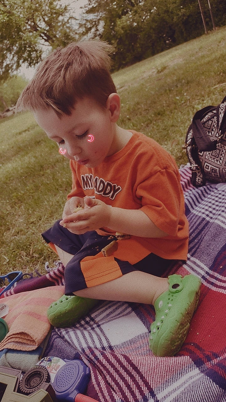 Ashton is registered to the contest to win money with this photo: baby, baby_toddler_clothing, child, fun, grass, green, happy, lap, lawn, leisure, person, play, recreation, sharing, shorts, sitting, sock, t_shirt, toddler, toy