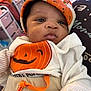 baby, infant, child, face, clothing, hat, pumpkin, orange, white, cute, portrait, indoor, soft_lighting, closeup, expression, newborn, person, apparel, sitting, blanket