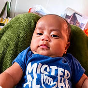 Jruziah joined the competition — help win amazing prizes! baby, blue_shirt, child, clothing, cushion, cute, expression, face, green, head, indoor, infant, person, portrait, relaxed, seated, skin, text_on_clothing, toddler, young_child