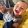 baby, smiling, child, infant, bedspread, bee_pattern, plush_toy, clothing, person, striped_shirt, hand, face, happy, indoors, portrait, cute, young_child, fabric, closeup, joyful