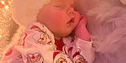 Tommie is registered to the contest to win money with this photo: baby, blanket, child, christmas, cozy, cute, face, festive, hat, holiday, holiday_decor, indoors, infant, pajamas, portrait, relaxed, santa_claus, sleeping, soft_lighting, warm