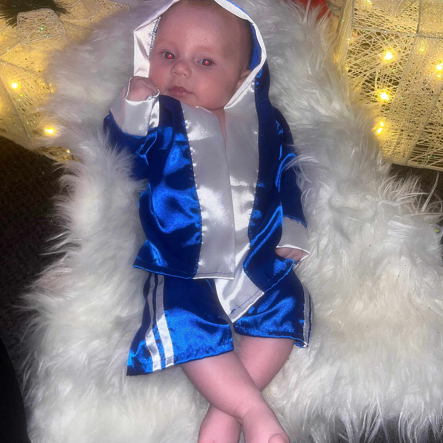 Tommie joined the competition — help win amazing prizes! baby, blue_robe, boxing_robe, carpet, child, crossed_legs, cute, decorations, face, feet, fluffy_rug, holiday, indoor, infant, lights, portrait, red_eye, relaxed, small_hands, soft_texture