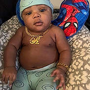 Adrian joined the competition — help win amazing prizes! baby, child, smiling_face, hat, pants, gold_necklace, gold_bracelet, spiderman_pillow, cushion, patterned_fabric, indoor, person, portrait, baby_clothing, accessory, relaxing, furniture, cute, young_child, seated