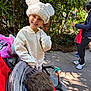 boy, casual_clothing, child, daylight, family, girl, greenery, happy, hat, hoodie, jacket, outdoor, park, person, plants, playful, smile, stroller, walking, white_hat