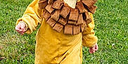 Lilly is registered to the contest to win money with this photo: child, toddler, lion_costume, yellow, brown, grass, outdoor, smiling, happy, cute, walking, costume, nature, greenery, playful, baby, face, hood, fun, joy