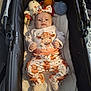 baby, infant, stroller, plush_toys, headband, cute, clothing, animal_print, cow, soft_lighting, cozy, blanket, indoor, child, portrait, white_socks, toy, fabric, relaxing, comfort