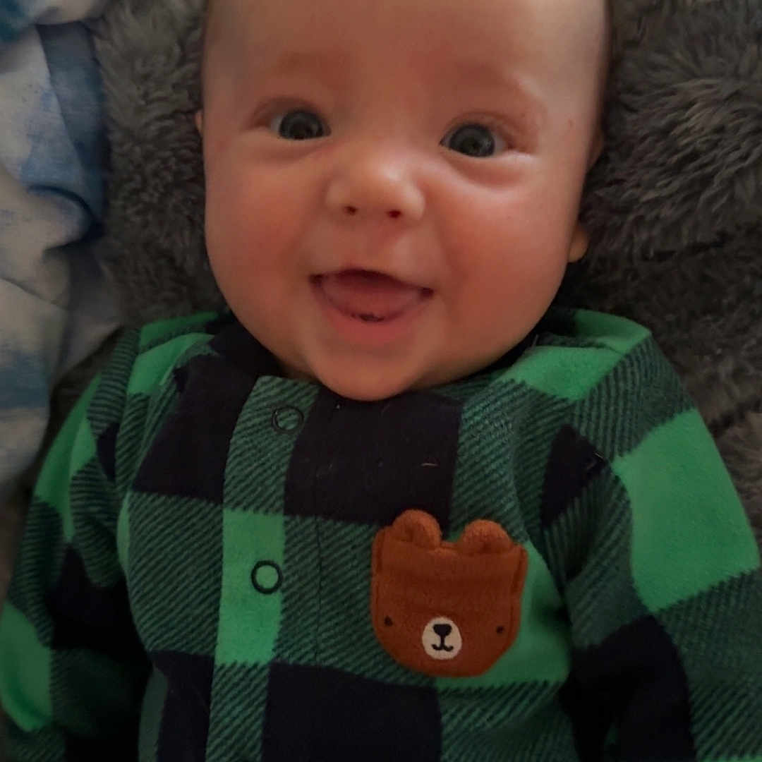 Ethan is registered to the contest to win money with this photo: applique, baby, bodypart, clothing, face, finger, hand, happy, head, hoodie, knitwear, newborn, pattern, person, photography, portrait, shirt, smile, sweater, sweatshirt