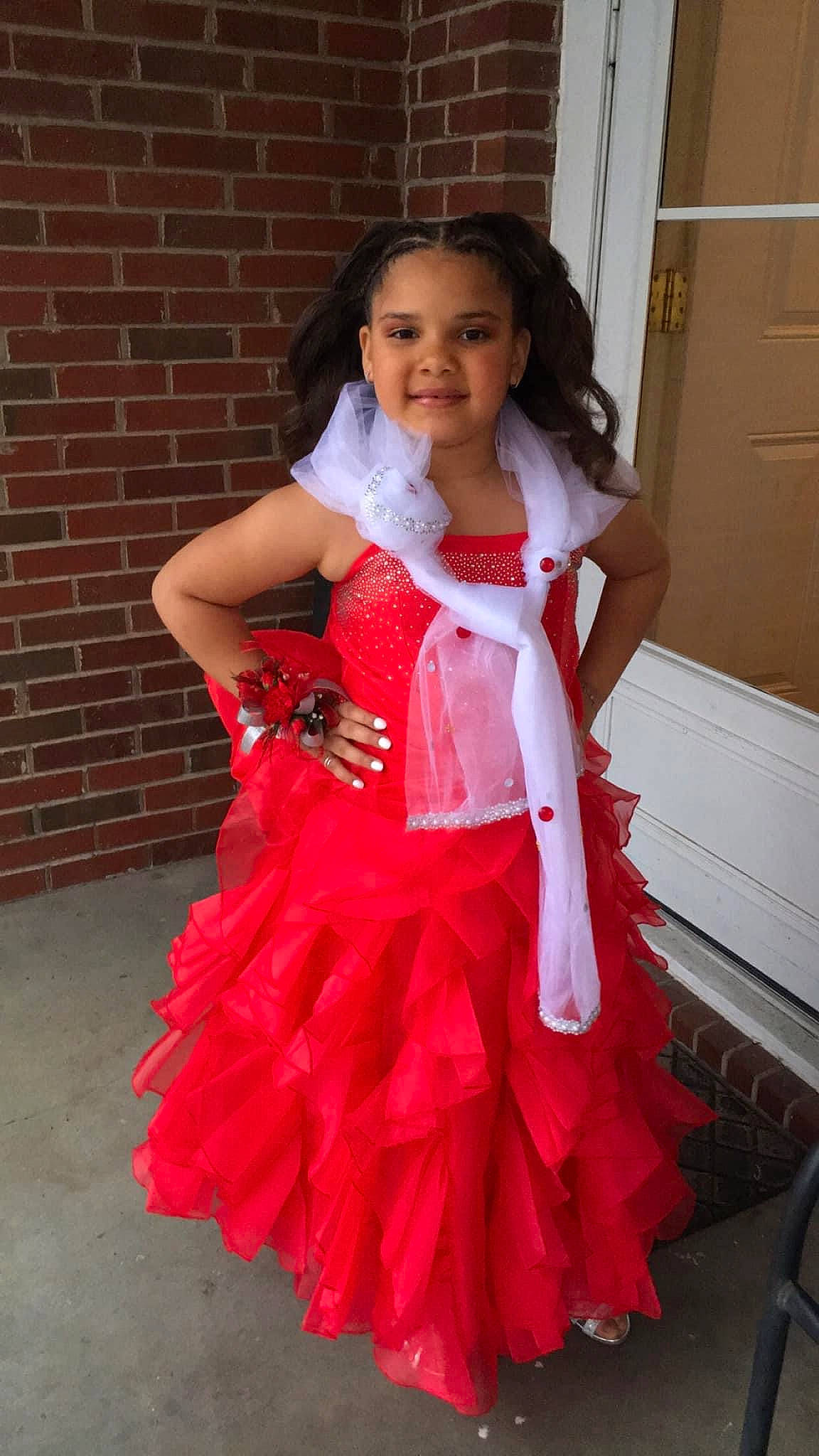 Gracelyn is registered to the contest to win money with this photo: brickwork, day_dress, door, dress, embellishment, event, fashion_design, formal_wear, gown, hair, happy, joy, long_hair, one_piece_garment, person, pink, ruffle, sleeve, smile, toddler