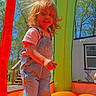 child, toddler, denim_overalls, boots, bounce_house, inflatable, outdoor, sunny, daylight, trees, blue_sky, grass, play, fun, smile, hair, portrait, person, happy, recreation