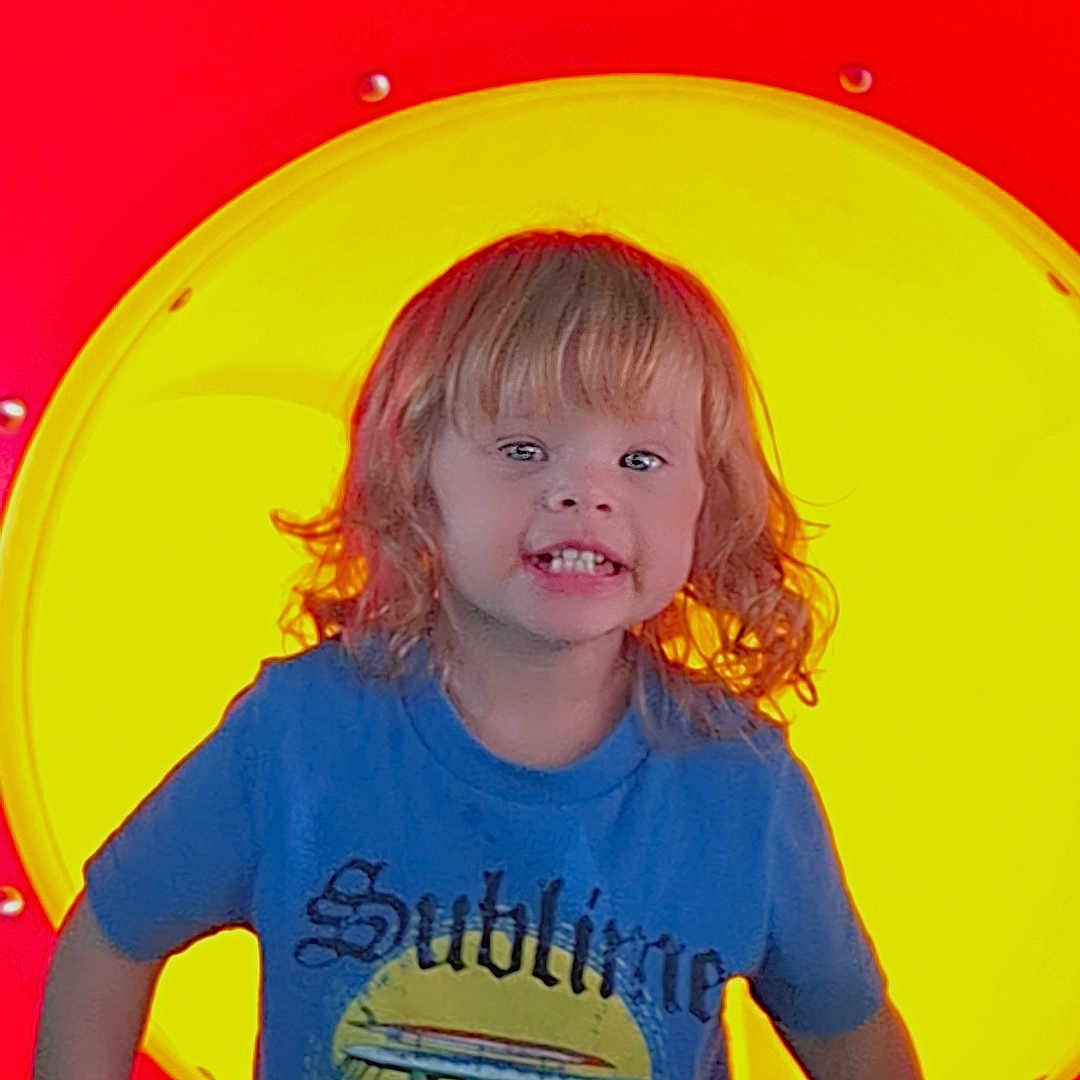 Nova joined the competition — help win amazing prizes! child, curly_hair, playground, tunnel, colorful, red, yellow, blue_tshirt, smile, happy, outdoor, fun, cute, person, young_child, play, casual_clothing, daylight, portrait, vibrant_colors