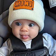 Hazel joined the competition — help win amazing prizes! baby, infant, hat, knit_hat, car_seat, harness, tongue_out, cute, child, clothing, black_straps, white_shirt, face, eyes, nose, mouth, expression, seat, safety, playful