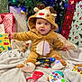 baby, blanket, celebration, child, christmas_lights, christmas_tree, colorful, cute, decorations, festive, happy, holiday, indoors, presents, reindeer_onesie, seasonal, smiling, socks, toys, warm_clothing