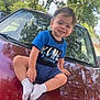 Myles Greco joined the competition — help win amazing prizes! toddler, child, smile, blue_shirt, white_socks, car, hood, outdoor, daylight, trees, reflection, grass, happy, casual_clothing, portrait, young_child, sidewalk, nature, parked_car, sunlight