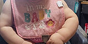 Scarlette joined the competition — help win amazing prizes! baby, child, high_chair, bib, smiling, indoors, wooden_wall, pants, winnie_the_pooh, cute, happy, infant, seatbelt, clothing, person, foot, hand, face, portrait, home