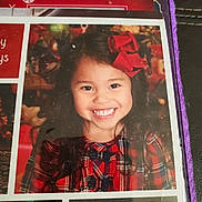Audrey is registered to the contest to win money with this photo: background, cheerful, child, clothing, colorful, cute, face, festive, girl, happy, holiday, indoor, long_hair, person, photograph, plaid_dress, portrait, red_bow, smile, young