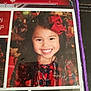 background, cheerful, child, clothing, colorful, cute, face, festive, girl, happy, holiday, indoor, long_hair, person, photograph, plaid_dress, portrait, red_bow, smile, young