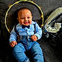 baby, boy, smiling, blue_shirt, bow_tie, suspenders, jeans, striped_socks, couch, gray_couch, balloon, number_4, fairy_lights, decorative_ring, celebration, indoors, happy, portrait, cute, child