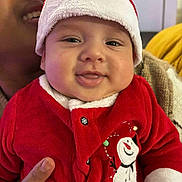 Aroon a rejoint le concours — aidez-le/la à gagner de superbes lots ! baby, child, smiling, face, red_clothing, santa_hat, holiday, festive, snowman, winter_wear, person, indoor, portrait, cute, happy, adult, hand, cozy, warm_clothing, closeup