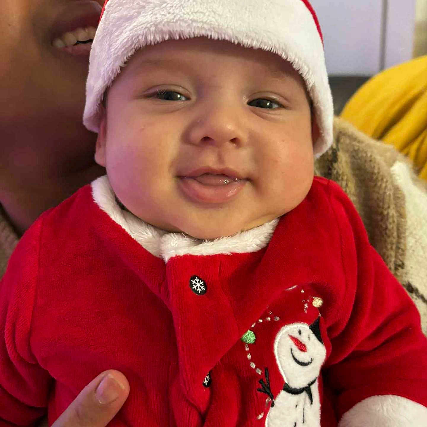 Aroon a rejoint le concours — aidez-le/la à gagner de superbes lots ! adult, baby, child, closeup, cozy, cute, face, festive, hand, happy, holiday, indoor, person, portrait, red_clothing, santa_hat, smiling, snowman, warm_clothing, winter_wear