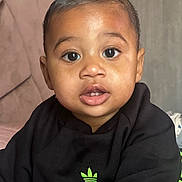 Djibril a rejoint le concours — aidez-le/la à gagner de superbes lots ! baby, child, face, eyes, mouth, clothing, sweatshirt, indoor, portrait, cute, infant, young_child, black_clothing, logo, curious, expression, skin, head, person, closeup