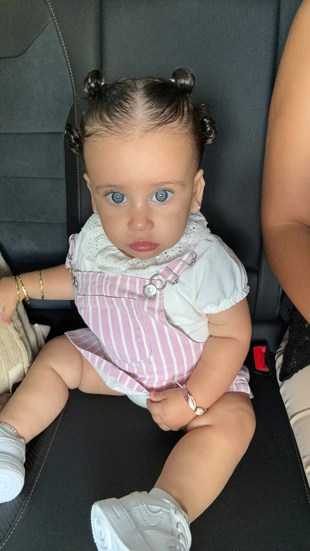 Yasmine a rejoint le concours — aidez-le/la à gagner de superbes lots ! baby, child, blue_eyes, hair_buns, pink_overall, white_tshirt, bracelet, earrings, car_seat, sneakers, cute, portrait, infant, fashion, looking_at_camera, serious_expression, indoor, person, skin, hand