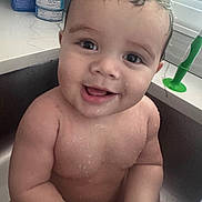Liam is registered to the contest to win money with this photo: baby, child, bath, sink, water, wet_skin, smile, happy, tooth, curly_hair, kitchen, countertop, green_brush, face, portrait, cute, infant, skin, person, domestic