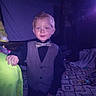 Zane joined the competition — help win amazing prizes! child, boy, toddler, portrait, bow_tie, vest, formalwear, smiling, standing, indoors, bedroom, bed, blanket, colorful, purple_lighting, flash_photography, patterned_bedding, short_hair, young_person, celebration