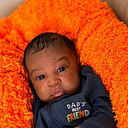 Karter is registered to the contest to win money with this photo: baby, infant, child, blanket, orange, clothing, navy_blue, face, portrait, cute, young, soft, cozy, expression, human, newborn, looking, sitting, indoors, sleepwear