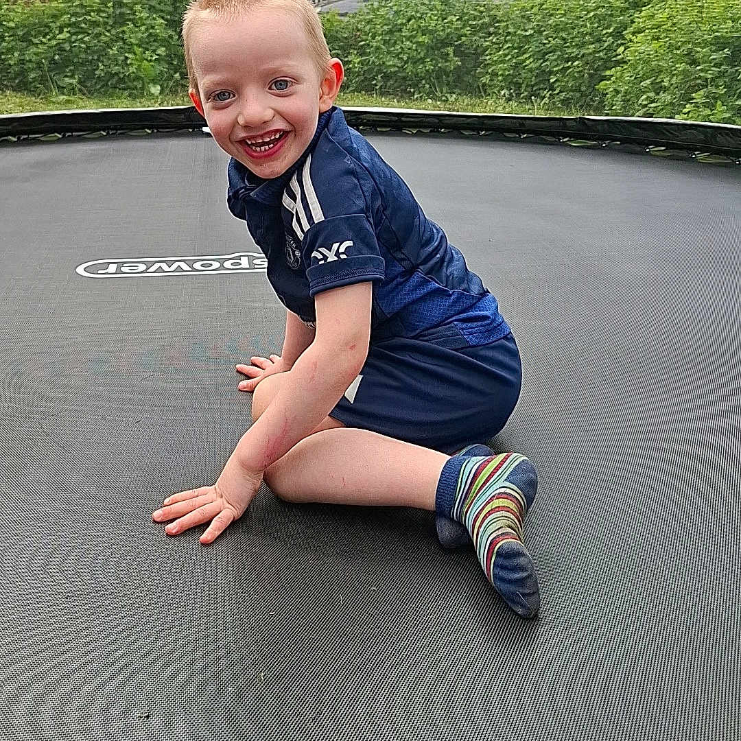 Jace Campbell is registered to the contest to win money with this photo: blue_clothing, boy, casual, child, daylight, fun, grass, greenery, happy, house, leisure, nature, outdoor, play, recreation, short_hair, smiling, socks, sporty, trampoline