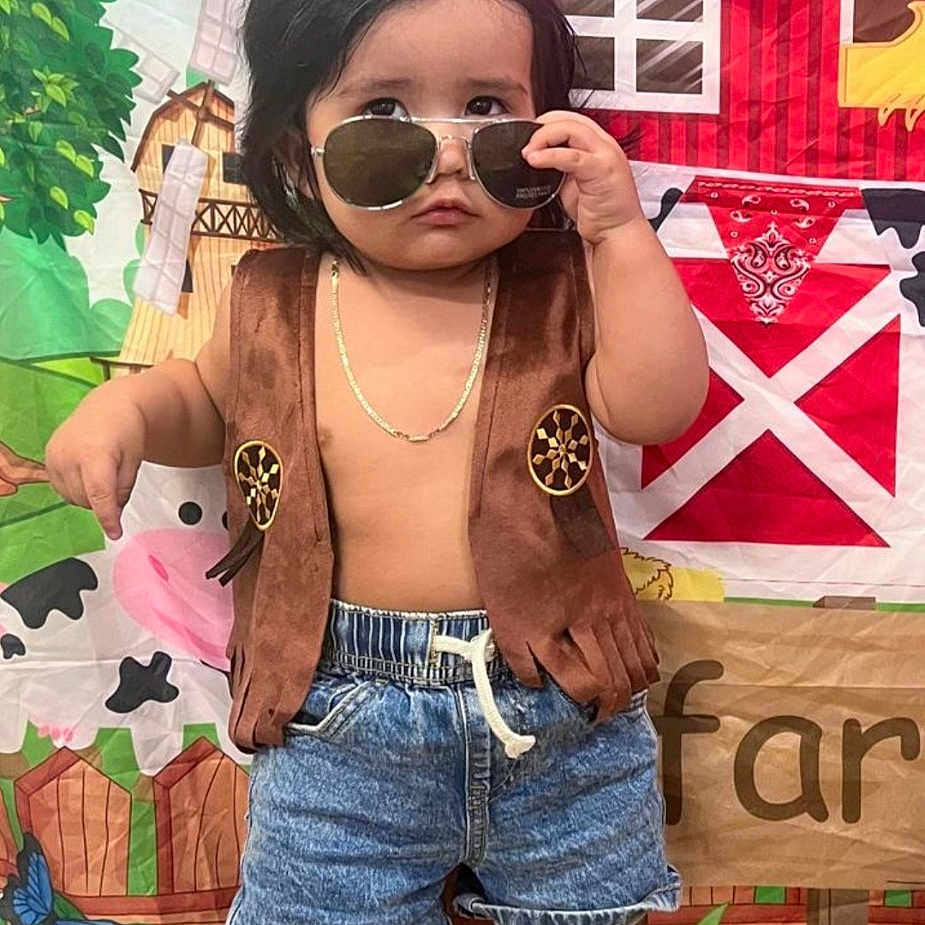 Ian is registered to the contest to win money with this photo: barn, boy, chain_necklace, child, colorful, cow, cowboy, cowboy_boots, cute, denim_shorts, farm_backdrop, greenery, indoor, playful, posing, serious_expression, short_hair, sunglasses, toy_theme, vest