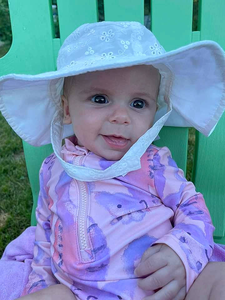 Sophia is registered to the contest to win money with this photo: baby, baby_toddler_clothing, blue, cheek, child, clothing, eye, grass, happy, hat, headgear, headwear, iris, lip, person, plant, purple, skin, smile, sun_hat